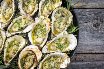 Barbecue overbaked fresh opened oyster with garlic and herbs offered as top view on a tray with...