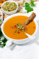 fresh soup of pumpkin and lentils on white background, closeup vertical