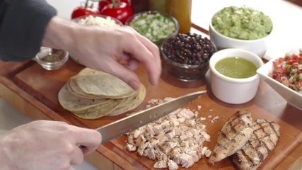 Chef chopping up grilled chicken breast for tacos