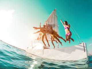 Happy crazy friends diving from sailing boat into the sea