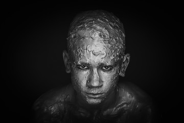 Fototapeta na wymiar Close-up of a man's face in clay. Monochrome portrait 