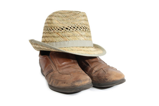 Old shoes and a straw hat on a white background