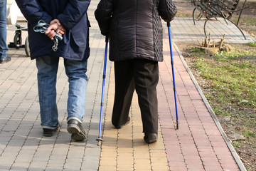 Old elderly man and woman walking with a cane