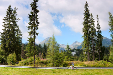 Summertime landscape, girl cyclist rides on the background of mountains High Tatras in the Slovakia