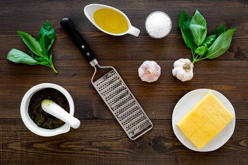 Ingredients for pesto sauce. Cheese, garlic, green basil, olive oil, salt near grater and mortar on...