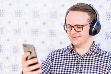 Young man with bluetooth headphones connected to smartphone