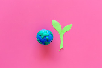 Planet, ecology. plastiline symbol of planet Earth globe and plant coutout on pink background top...