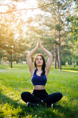 Young beautiful girl practicing yoga in the park. Woman in sportswear. Healthy lifestyle.