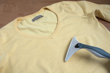 Fuzz remover on yellow fabric with fuzz balls.