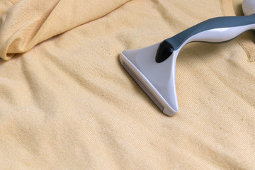 Fuzz remover on yellow fabric with fuzz balls.