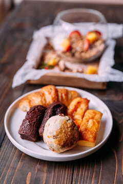 Fresh baked goods on white dish including scone, croissant, financier and chocolate financier.