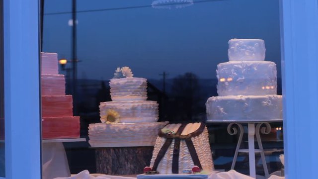 Pan from right to left of a small town bakery's display window with delicious looking cakes.