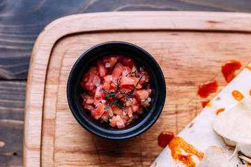 Meat kebab with chips topping with sauce and served with tomato salad on wooden plate.