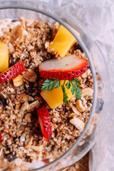 Close up Oatmeal served in glass cup including low-fat yogurt, fresh strawberry and diced mango for refresh your day.