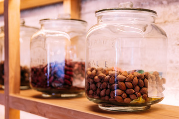 Almond in a glass jar place on the wooden shelf.