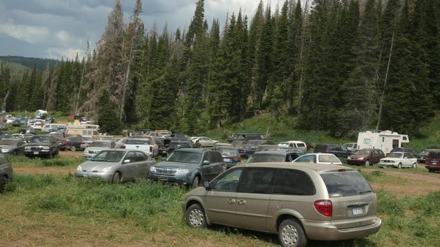Cars parked in forest at rainbow gathering.