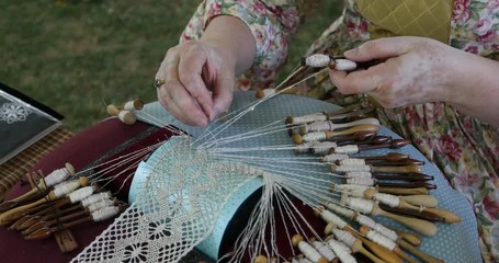 Historic handmade lace weaving woman. Bobbin lace is a textile made by braiding and twisting lengths of thread by hand. Hobby for highly homemade delicate clothing and decoration and art.