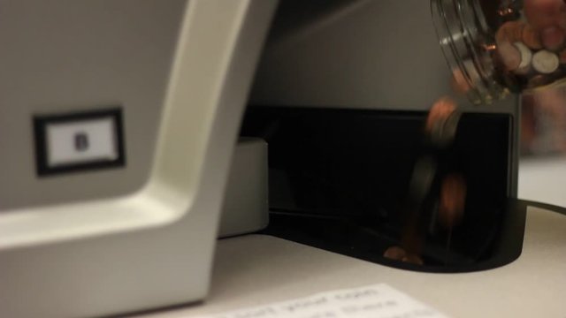 Glass jar of change being pored into a machine that counts money.