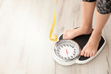 Woman with tape measuring her weight using scales on floor. Healthy diet