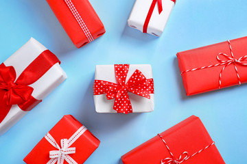 Beautifully wrapped gift boxes on color background, top view