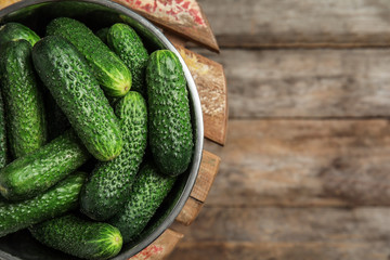 Bowl with ripe fresh cucumbers on table, top view