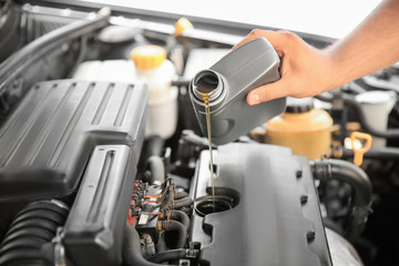 Obraz premium Mechanic pouring oil into car engine, closeup