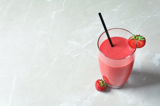 Glass with tasty strawberry smoothie on table
