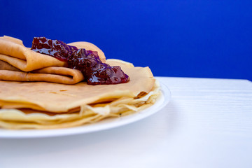 Close up Russian blini pancakes witg glass of milk and strawberries am on blue background ....