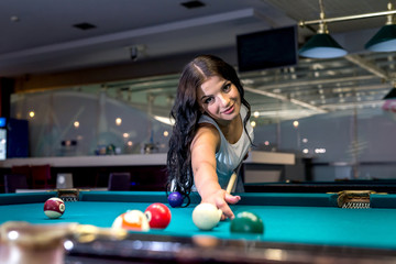 Beautiful brunette woman playing billiard in pub