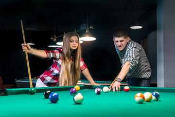 Fototapeta premium Young couple playing billiard, woman looking after boyfriend