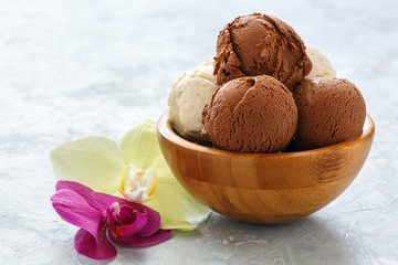 Vanilla and chocolate ice cream balls in a wooden bowl.