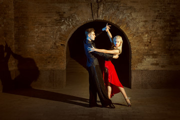 Beautiful young couple dancing tango in the twilight.