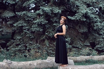 Slender brunette in a black dress in the park