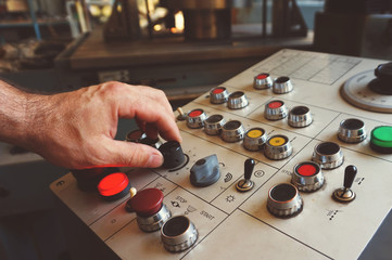 The worker uses the control panel of the CNC machine to process the material.