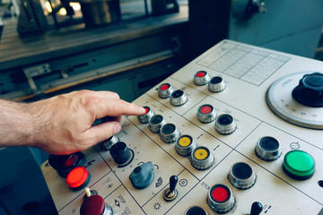 The worker uses the control panel of the CNC machine to process the material.