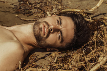 Strong face sport sexy male model on the sea shore background with sand and water on the beach on the sunset