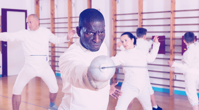 African American fencer practicing effective fencing techniques in training room - Powered by Adobe