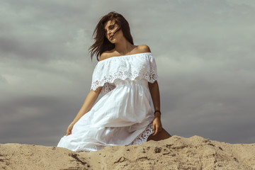 Fototapeta na wymiar Female beauty girl model brunette in a dress on the mountain and dessert sand font