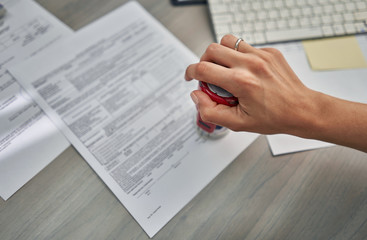 girl in the office puts a stamp on the documents