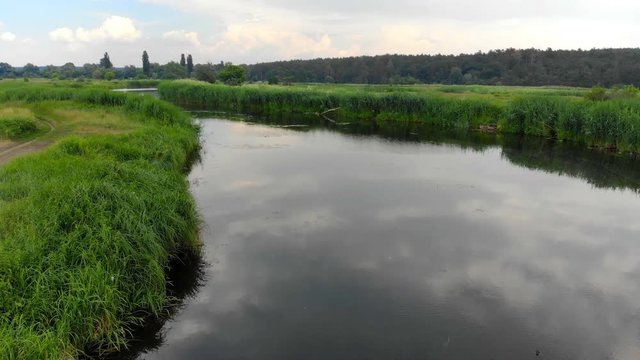 Aerial view of the river, movement along the bends and water surface and the reflection of the sun and sky in the mirror surface of the river