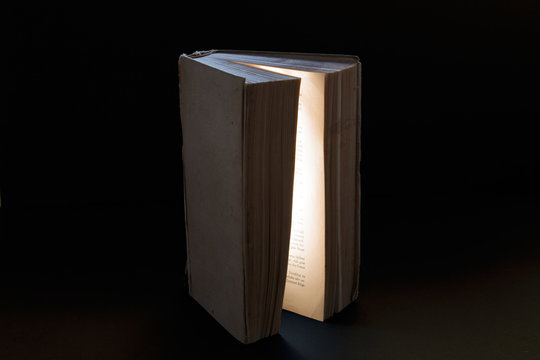 offenes buch mit schwarzem hintergrund leuchtet