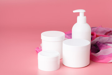 Cosmetic cream container and pink flowers on pink plaint  background