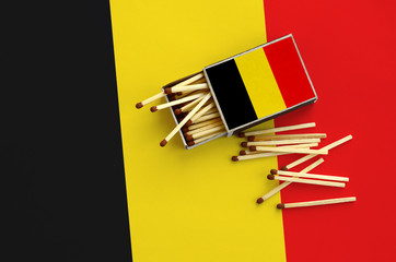 Belgium flag  is shown on an open matchbox, from which several matches fall and lies on a large flag