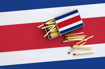 Costa Rica flag  is shown on an open matchbox, from which several matches fall and lies on a large...