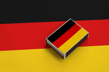 Germany flag  is pictured on a matchbox that lies on a large flag