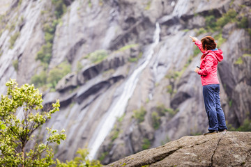 Woman on mountain rock enjoying beautiful view