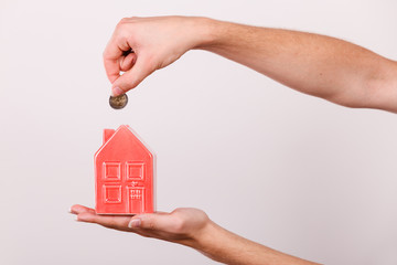 Man putting coin into house piggybank