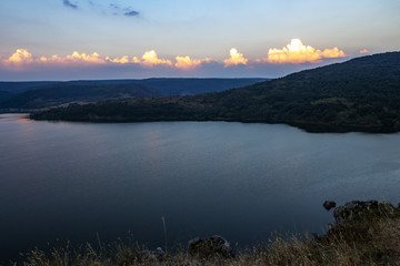 August sunset view to Pchelina Dam, Bulgaria with a row of sunlit clouds from the rocks next to the medieval non-functional Church of St. John Letni