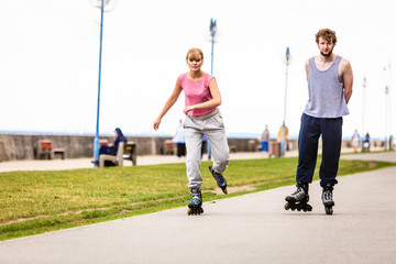 Friends rollerblading together have fun in park.