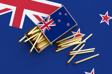 New Zealand flag  is shown on an open matchbox, from which several matches fall and lies on a large...